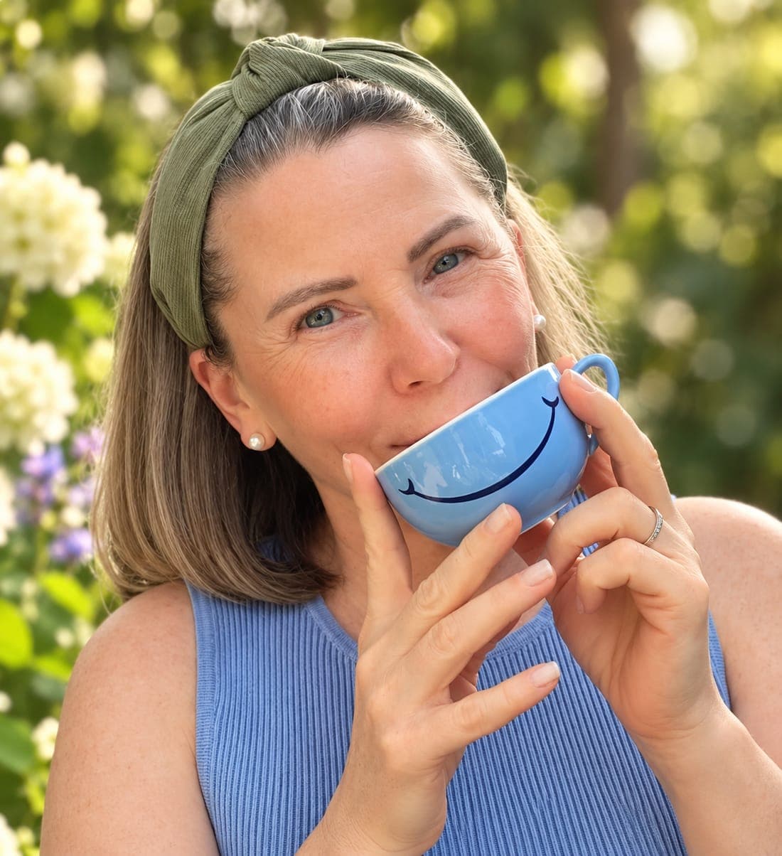 Dani trinkt aus einer blauen Tasse im Garten
